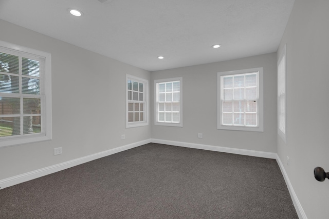 spare room with recessed lighting, dark carpet, and baseboards