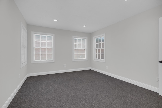 empty room with dark carpet, recessed lighting, plenty of natural light, and baseboards