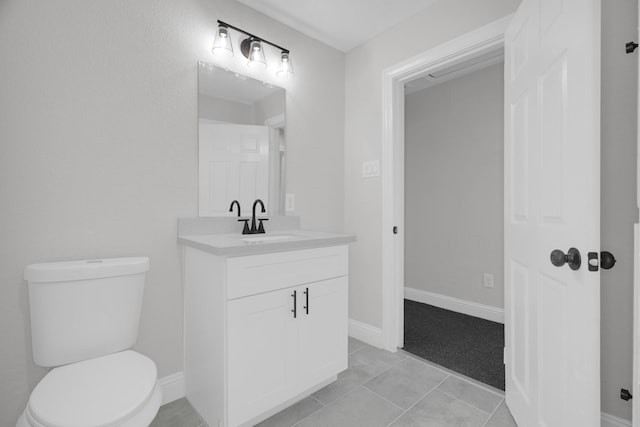 bathroom with toilet, tile patterned flooring, vanity, and baseboards