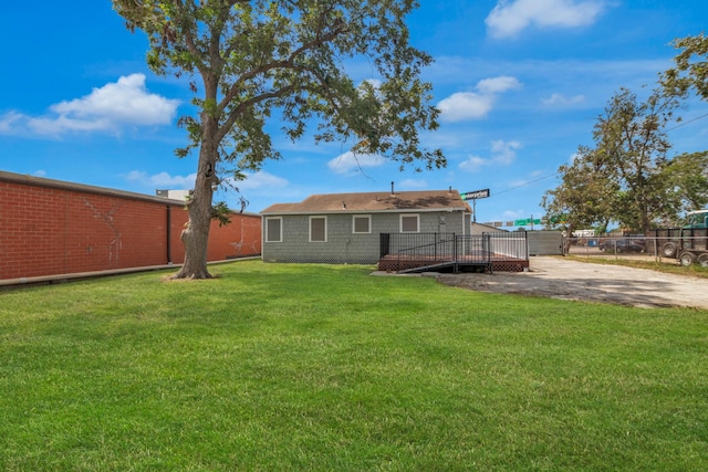 back of property with fence, a deck, and a yard