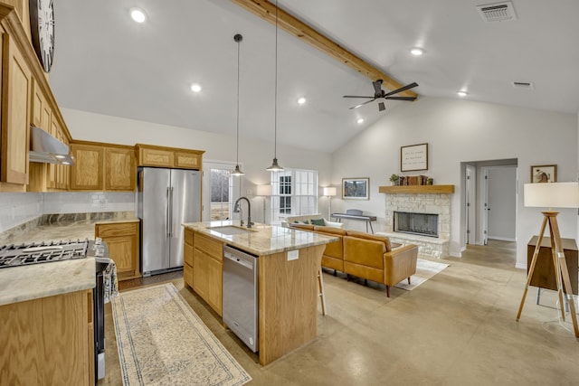 kitchen featuring sink, a kitchen island with sink, stainless steel appliances, light stone countertops, and decorative light fixtures