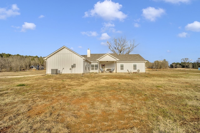 rear view of house with cooling unit and a yard