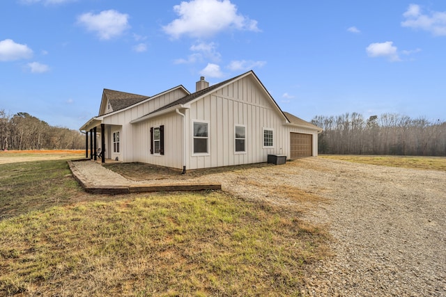 view of side of property with a garage, a yard, and central air condition unit