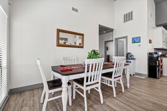 308 Lakeshore S, Onalaska, TX 77360 - dining room featuring a towering ceiling, baseboards, light wood-style flooring, and visible vents