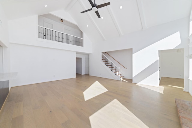 unfurnished living room featuring beam ceiling, light hardwood / wood-style flooring, high vaulted ceiling, and ceiling fan