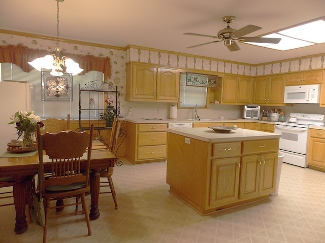 kitchen with pendant lighting, sink, white appliances, a kitchen island, and ceiling fan with notable chandelier