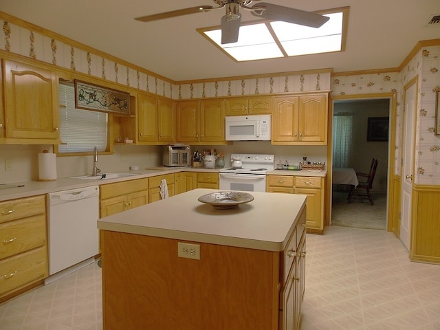 kitchen with a kitchen island, sink, ornamental molding, ceiling fan, and white appliances