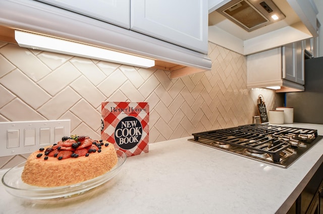 kitchen with stainless steel gas stovetop, premium range hood, white cabinets, and backsplash