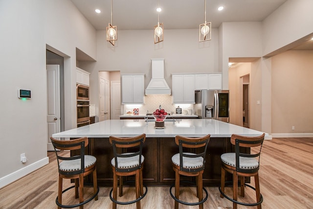 kitchen featuring white cabinetry, appliances with stainless steel finishes, a large island, and custom range hood