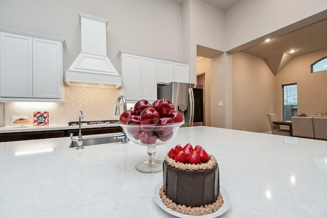 kitchen featuring sink, tasteful backsplash, white cabinets, stainless steel fridge with ice dispenser, and custom exhaust hood