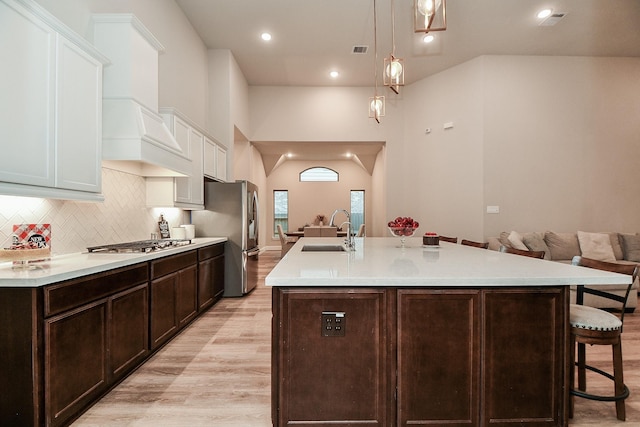 kitchen featuring a kitchen bar, sink, an island with sink, stainless steel appliances, and white cabinets