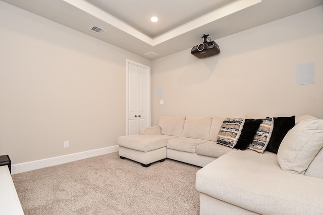 living room featuring carpet and a tray ceiling