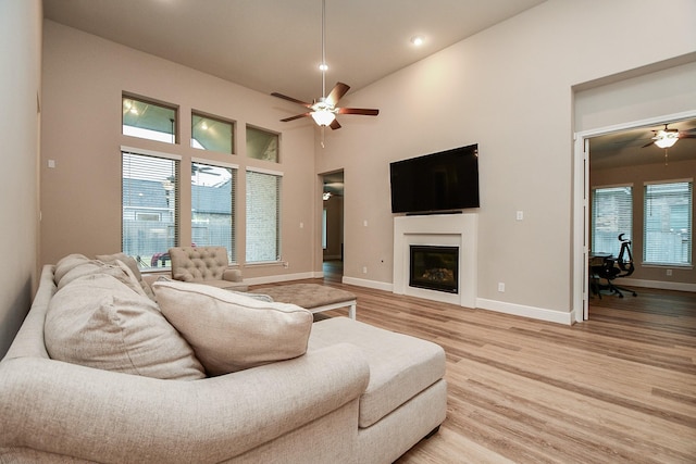 living room featuring a towering ceiling, ceiling fan, and light hardwood / wood-style floors