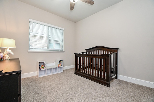 carpeted bedroom featuring ceiling fan and a crib