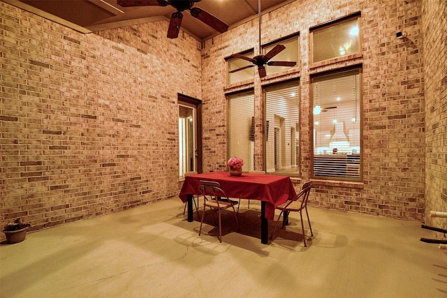 interior space with ceiling fan, brick wall, carpet flooring, and a towering ceiling