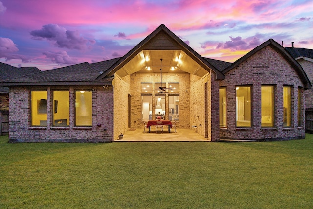 back house at dusk with a lawn and a patio area