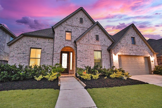 french country home featuring a garage and a yard