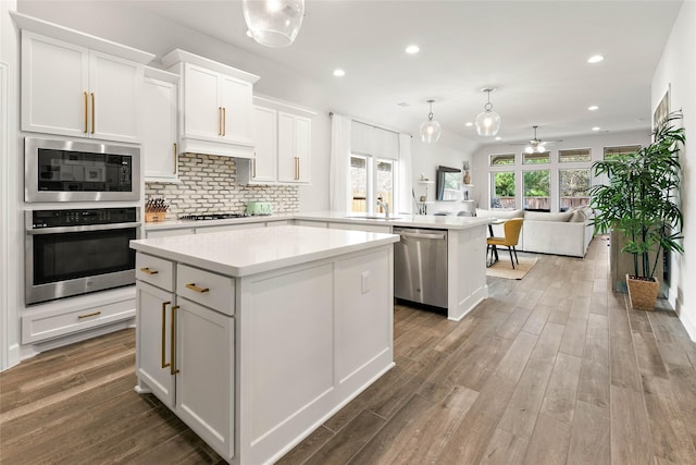 kitchen featuring a kitchen island, appliances with stainless steel finishes, white cabinetry, decorative backsplash, and kitchen peninsula