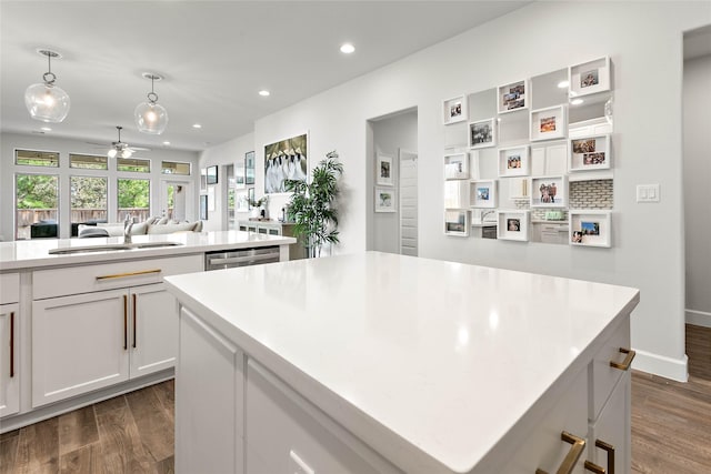 kitchen with a kitchen island, dark hardwood / wood-style floors, white cabinetry, sink, and hanging light fixtures