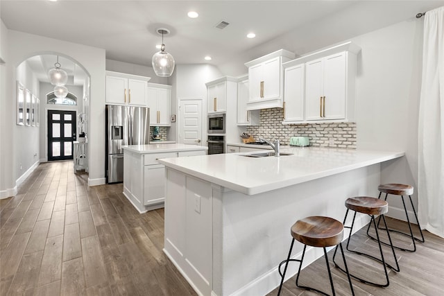 kitchen with pendant lighting, sink, appliances with stainless steel finishes, a kitchen breakfast bar, and kitchen peninsula