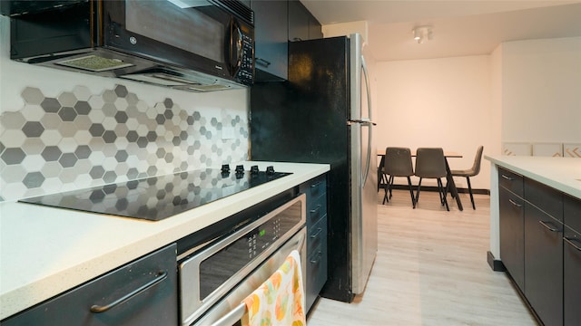 kitchen with tasteful backsplash, black appliances, and light hardwood / wood-style floors