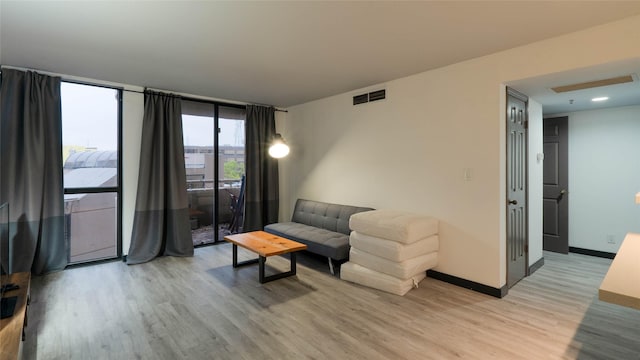 living room with a wall of windows and light hardwood / wood-style floors