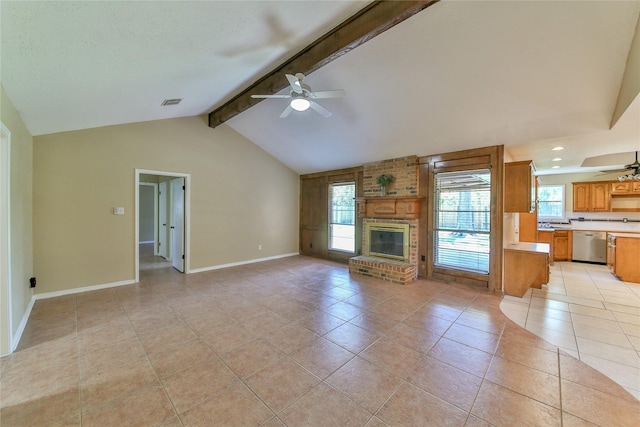 unfurnished living room with light tile patterned floors, a fireplace, lofted ceiling with beams, and a healthy amount of sunlight