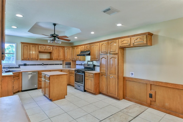 kitchen with appliances with stainless steel finishes, sink, a center island, ceiling fan, and a tray ceiling