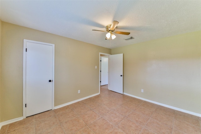 spare room with ceiling fan, a textured ceiling, and light tile patterned floors