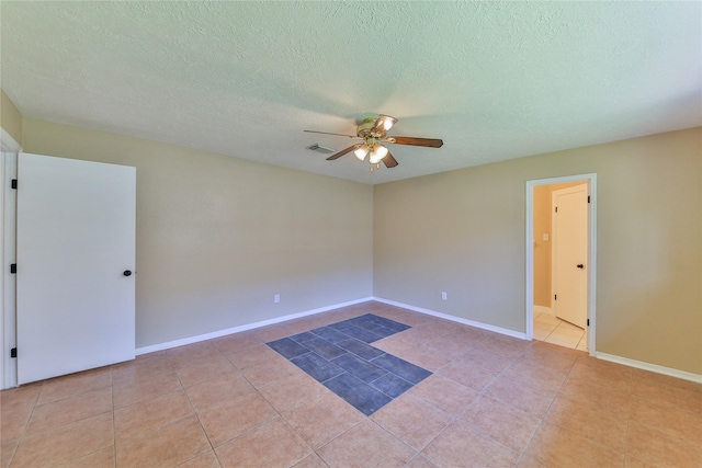 empty room with light tile patterned flooring, ceiling fan, and a textured ceiling