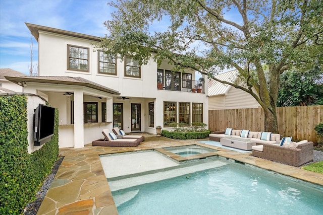 rear view of house with a swimming pool with hot tub, ceiling fan, outdoor lounge area, a patio area, and a balcony