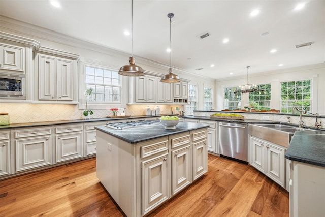 kitchen featuring sink, crown molding, a kitchen island, pendant lighting, and stainless steel appliances