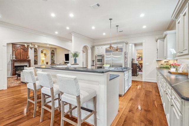 kitchen with a kitchen bar, white cabinetry, pendant lighting, stainless steel appliances, and a large island