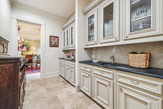 kitchen featuring sink, crown molding, an inviting chandelier, backsplash, and cream cabinetry