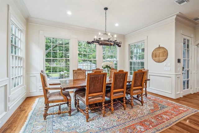 dining area with a notable chandelier, ornamental molding, a healthy amount of sunlight, and light wood-type flooring