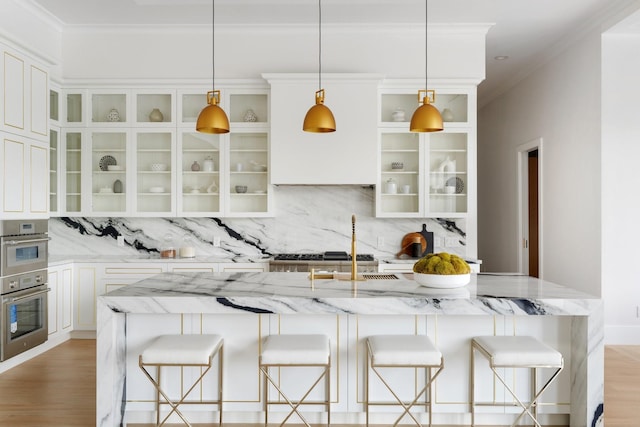 kitchen featuring light wood-type flooring, crown molding, backsplash, and a kitchen breakfast bar