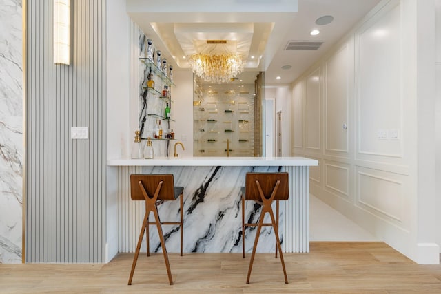 bar with visible vents, a decorative wall, indoor wet bar, and wood finished floors