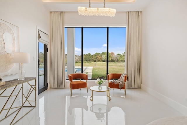 living area featuring a chandelier and baseboards