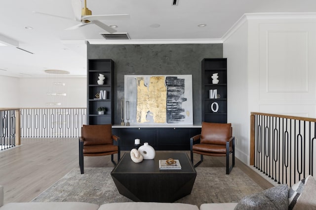 interior space featuring ceiling fan, crown molding, visible vents, and wood finished floors