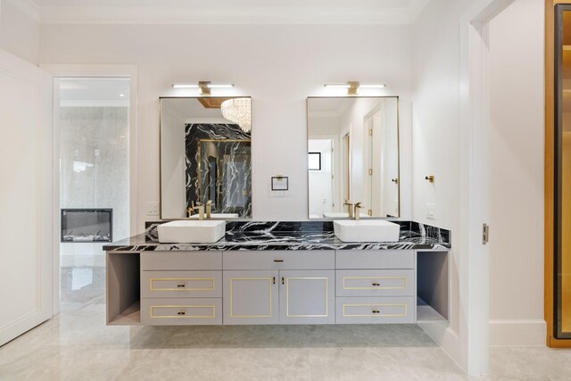 full bathroom with ornamental molding, a walk in closet, a sink, and double vanity