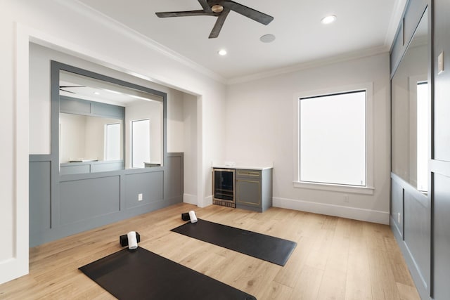 workout area featuring ornamental molding, beverage cooler, light wood finished floors, and a ceiling fan