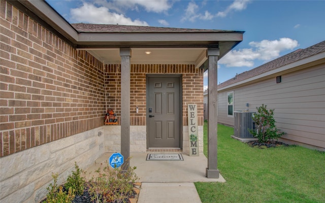 entrance to property featuring central AC unit and a lawn