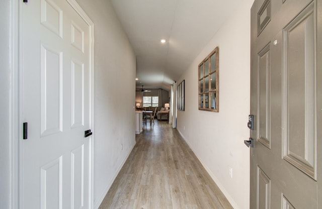 hall with lofted ceiling and light hardwood / wood-style flooring