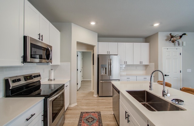 kitchen featuring stainless steel appliances, sink, white cabinets, and light hardwood / wood-style flooring