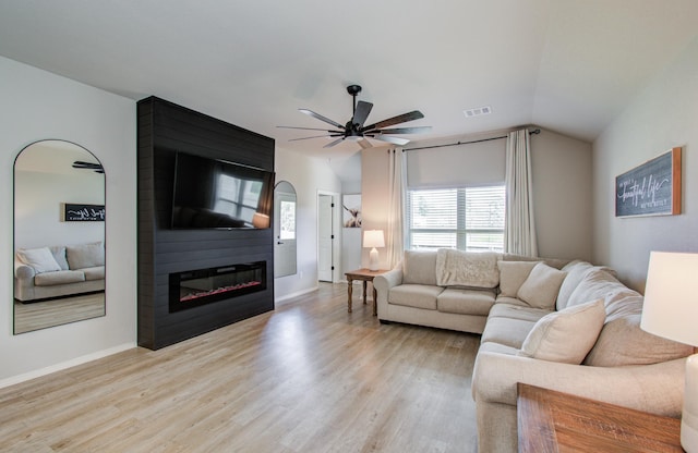 living room with light hardwood / wood-style flooring, a fireplace, ceiling fan, and vaulted ceiling