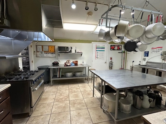 kitchen with exhaust hood, rail lighting, light tile patterned floors, and high end range