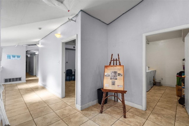 corridor featuring vaulted ceiling and light tile patterned floors