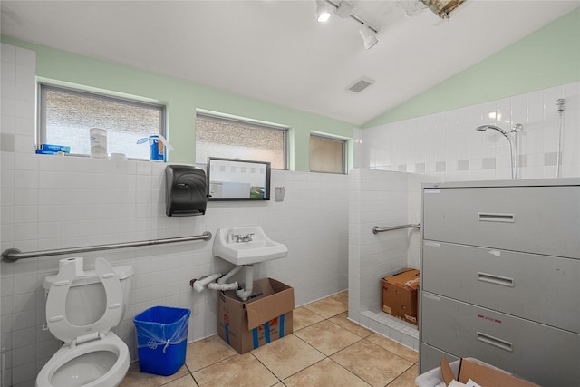 bathroom with lofted ceiling, tile walls, tile patterned floors, toilet, and walk in shower