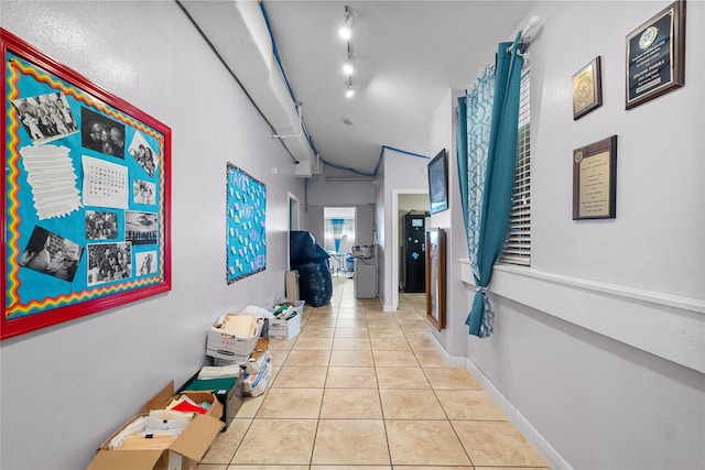 hall with rail lighting and light tile patterned floors