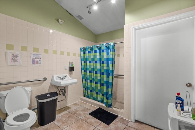 bathroom with vaulted ceiling, tile walls, tile patterned flooring, walk in shower, and toilet